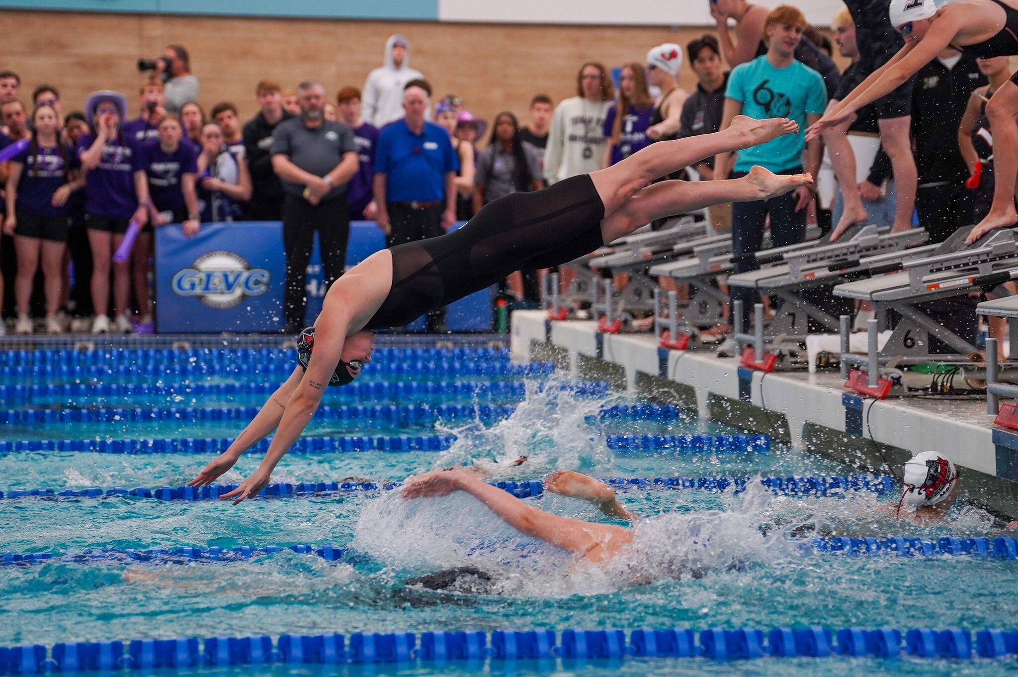 Athlete jumping from Xcellerator swimming starting blocks at indoor competitive pool