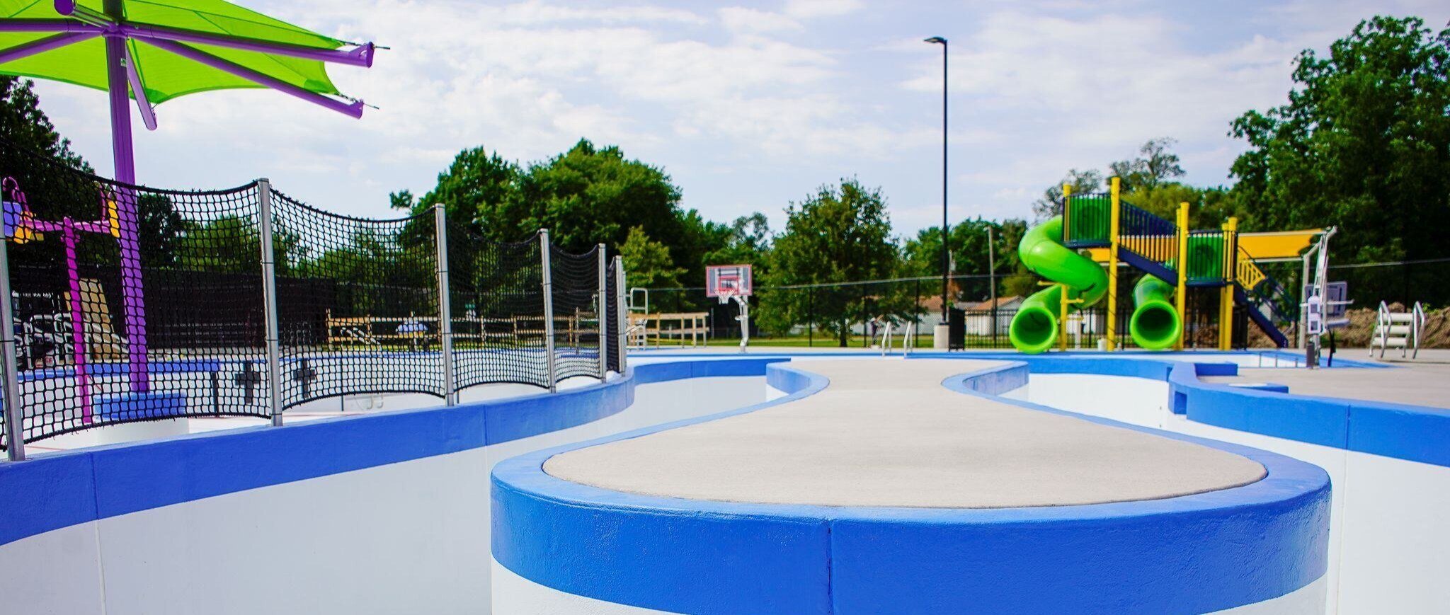 Outdoor pool featuring a poolside slide, stainless steel pool rails, and an ADA handicap pool chair lift